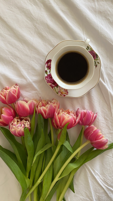 A Cup of Coffee and Pink Flowers on White Textile